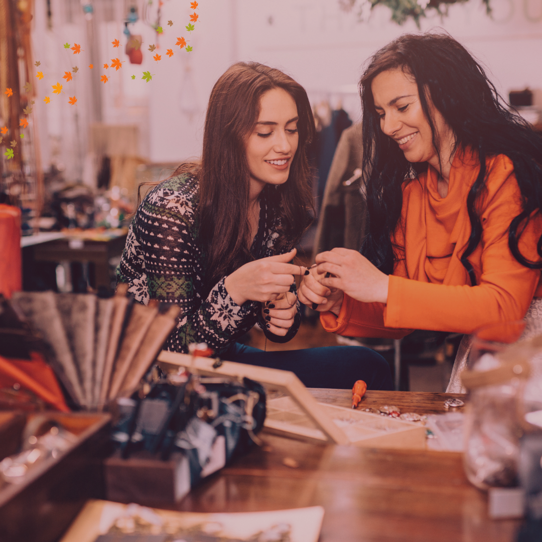 Fall jewelry flat lay with layered necklaces, beaded bracelets, and gemstone rings on a cozy sweater.