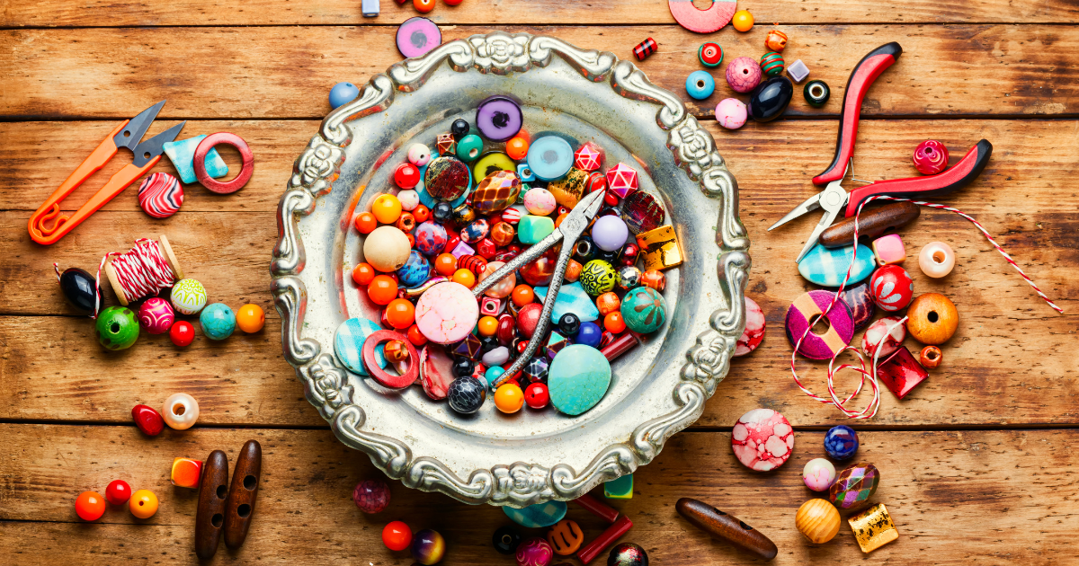 A flat lay of various beaded jewelry pieces, including bracelets, necklaces, and earrings, surrounded by loose beads and jewelry-making tools.