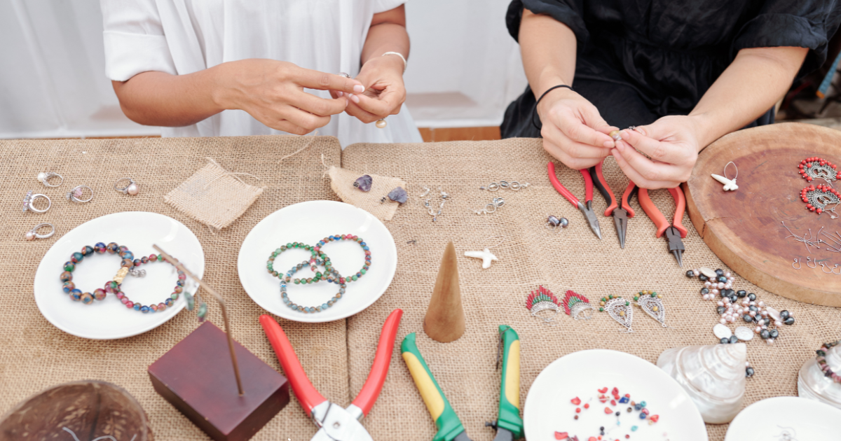 Artisan wire wrapping a gemstone with silver-plated wire for a piece of jewelry.