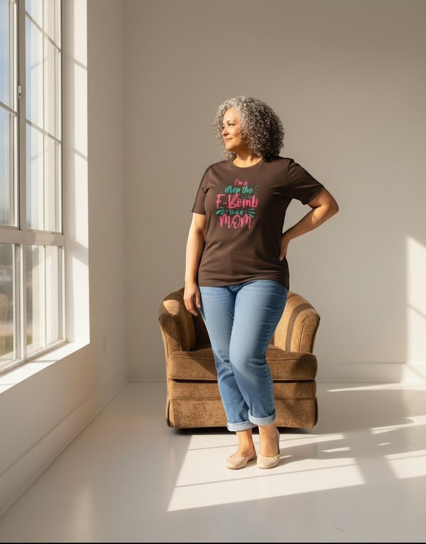 Woman relaxing in chair wearing brown “Drop the F-Bomb Mom” t-shirt, a comfy and relatable mom style.