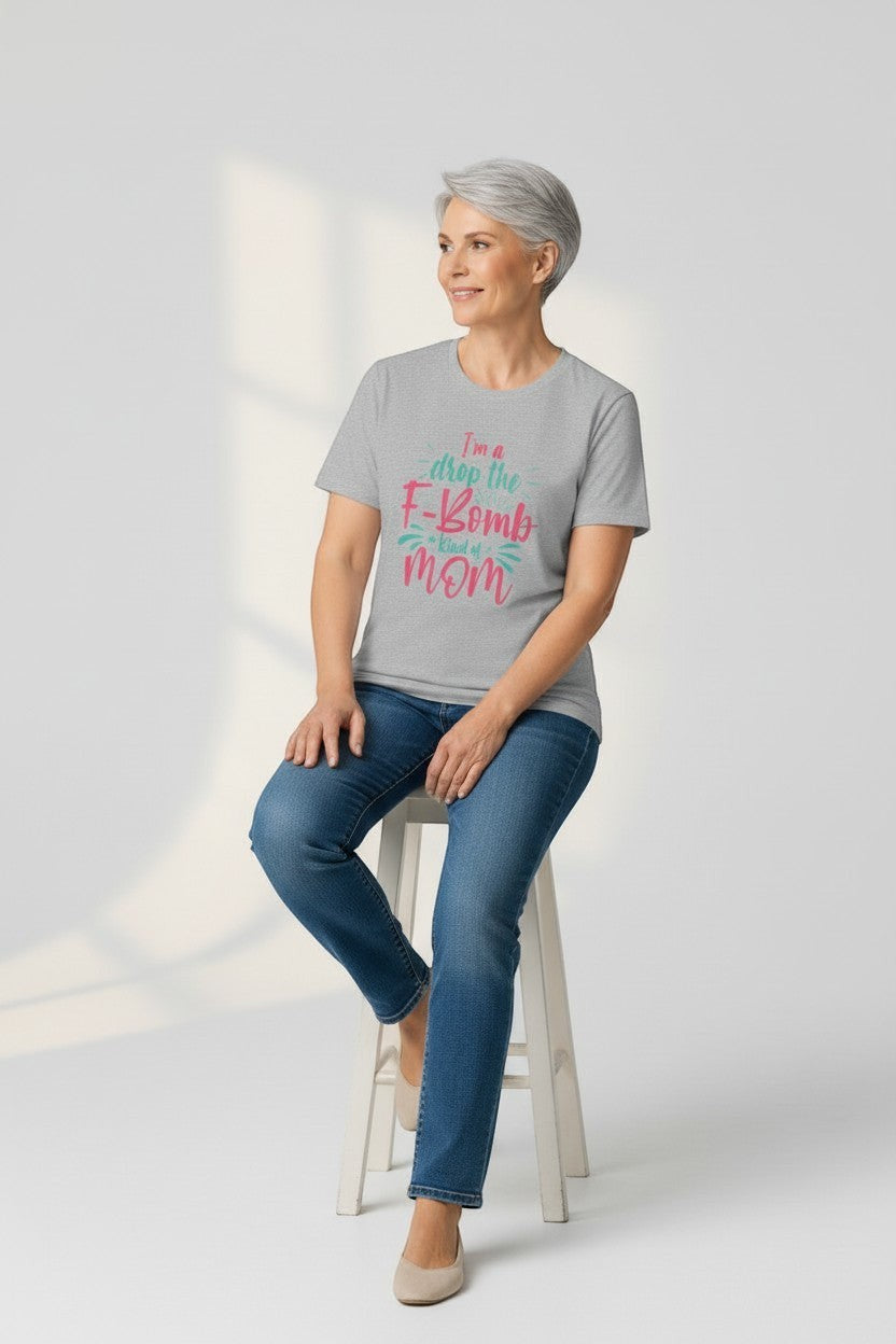 Woman sitting wearing grey “Drop the F-Bomb Mom” t-shirt, a comfy and relatable style.