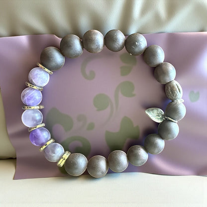 Jena Jewelry amethyst, ebony wood, and hematite stretch bracelet with gold spacers. Features a small silver leaf charm.