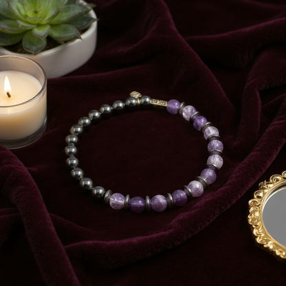 Jena Jewelry amethyst, hematite, and black onyx beaded stretch bracelet with silver accents, styled with a candle and succulent.