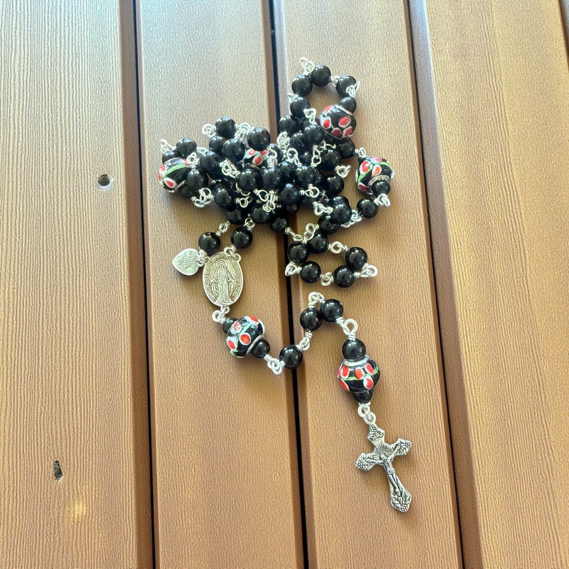 Jena Jewelry hand-wrapped rosary with black obsidian beads and floral lampwork glass beads, featuring a base metal crucifix and medallion.