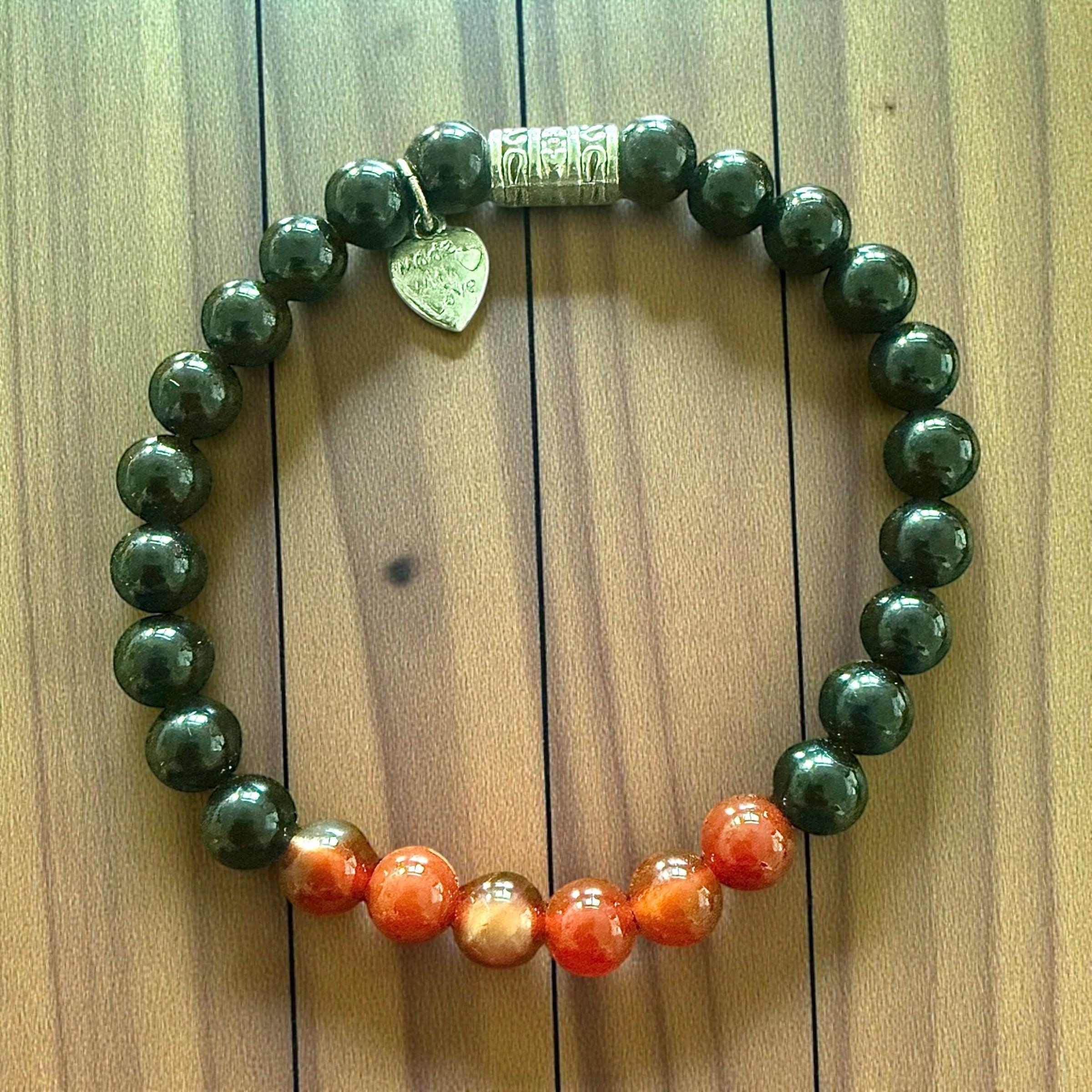 Jena Jewelry black onyx and carnelian beaded stretch bracelet with silver charm and clasp. Features matte black and vibrant orange-red stones.