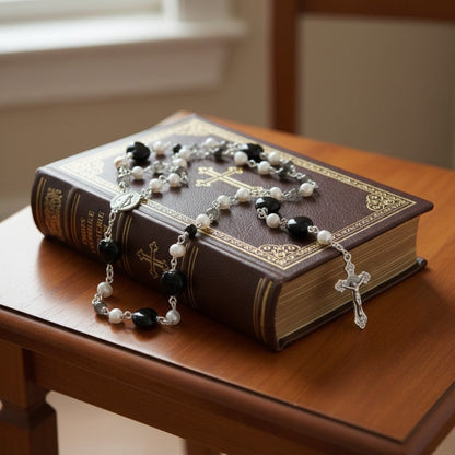 Jena Jewelry black porcelain heart, freshwater pearl, and black onyx rosary on a leather-bound book.