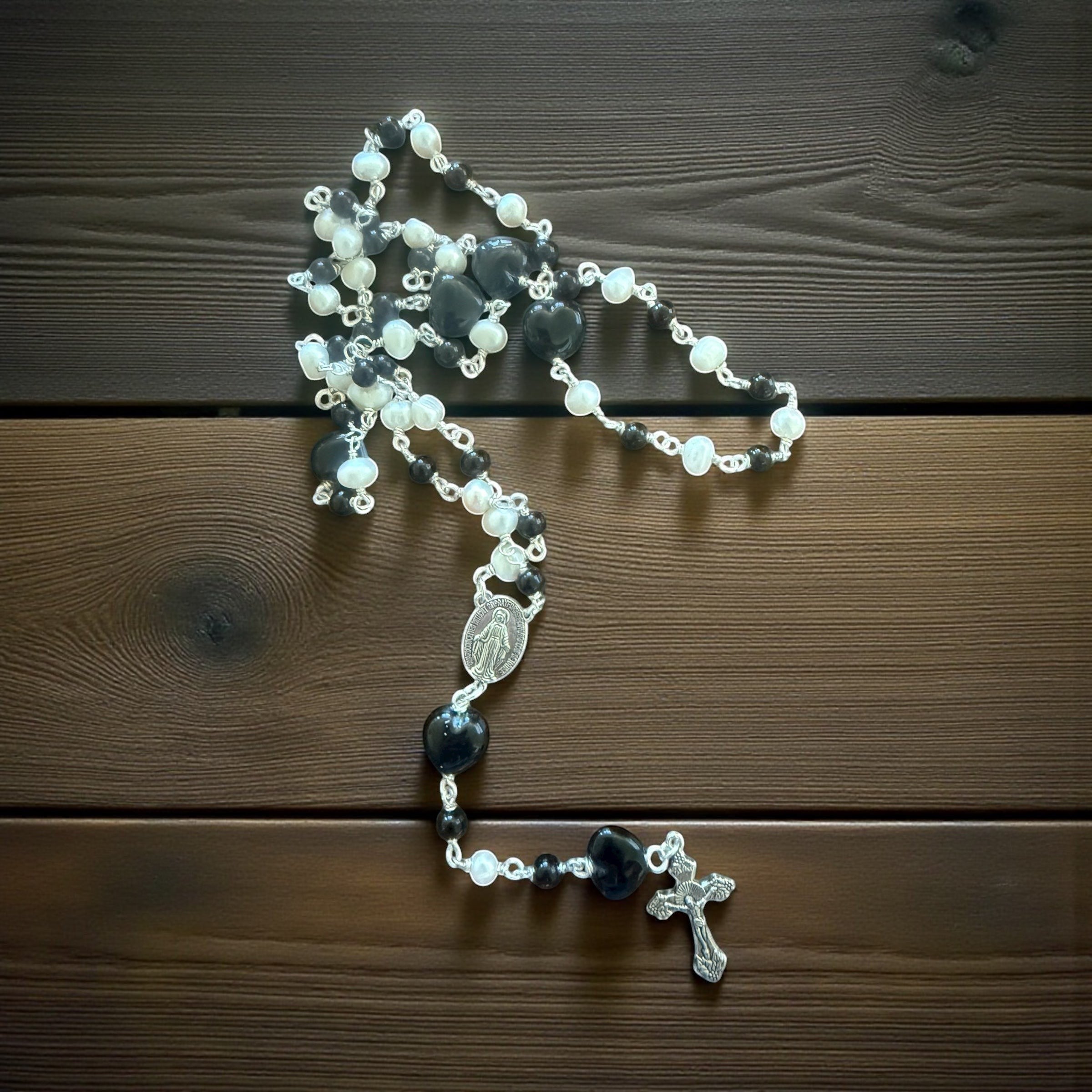 Jena Jewelry rosary with freshwater pearls, black onyx beads, and a black porcelain heart, finished with a silver cross and medallion.