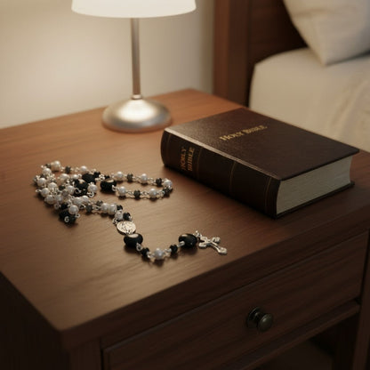 Jena Jewelry rosary with freshwater pearls, black onyx beads, and a black porcelain heart centerpiece. A Holy Bible rests nearby.