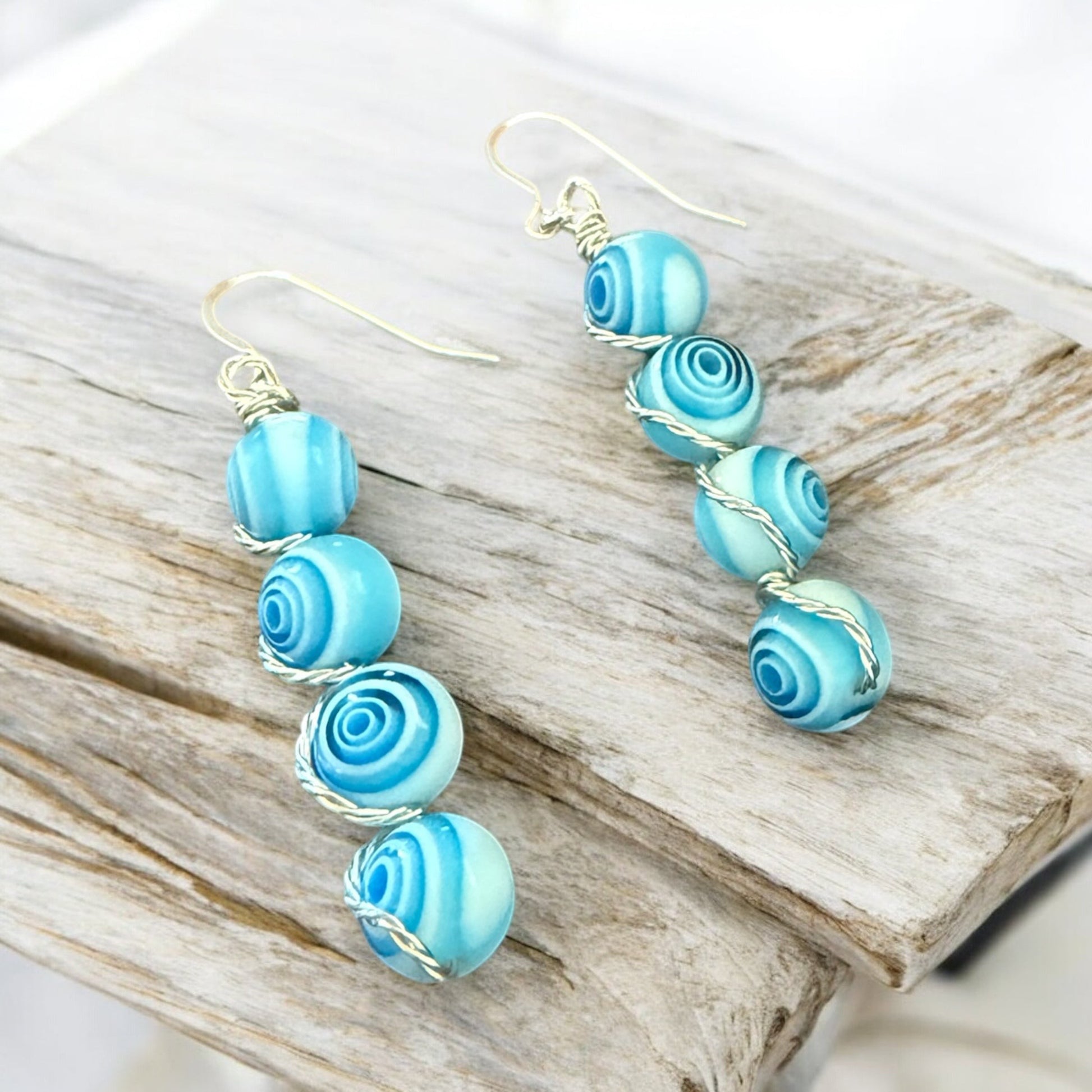 Jena Jewelry stacked blue glass bead drop earrings with silver-tone wire wrapping on hypoallergenic ear wires.