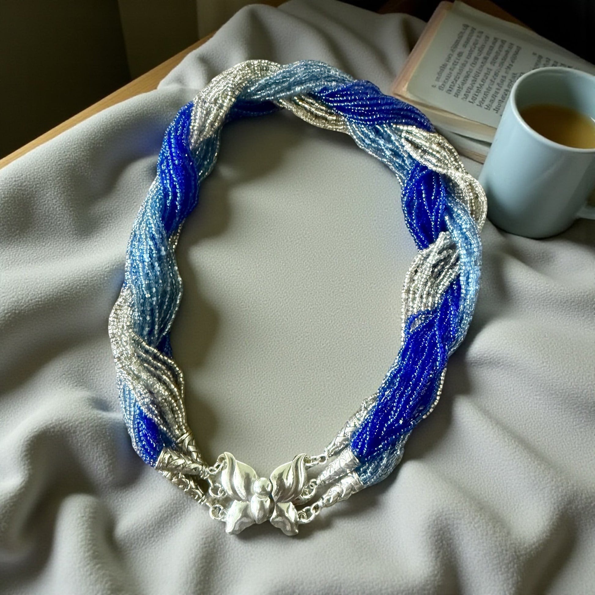 Jena Jewelry multi-strand braided necklace with blue and silver glass seed beads and a silver clasp.