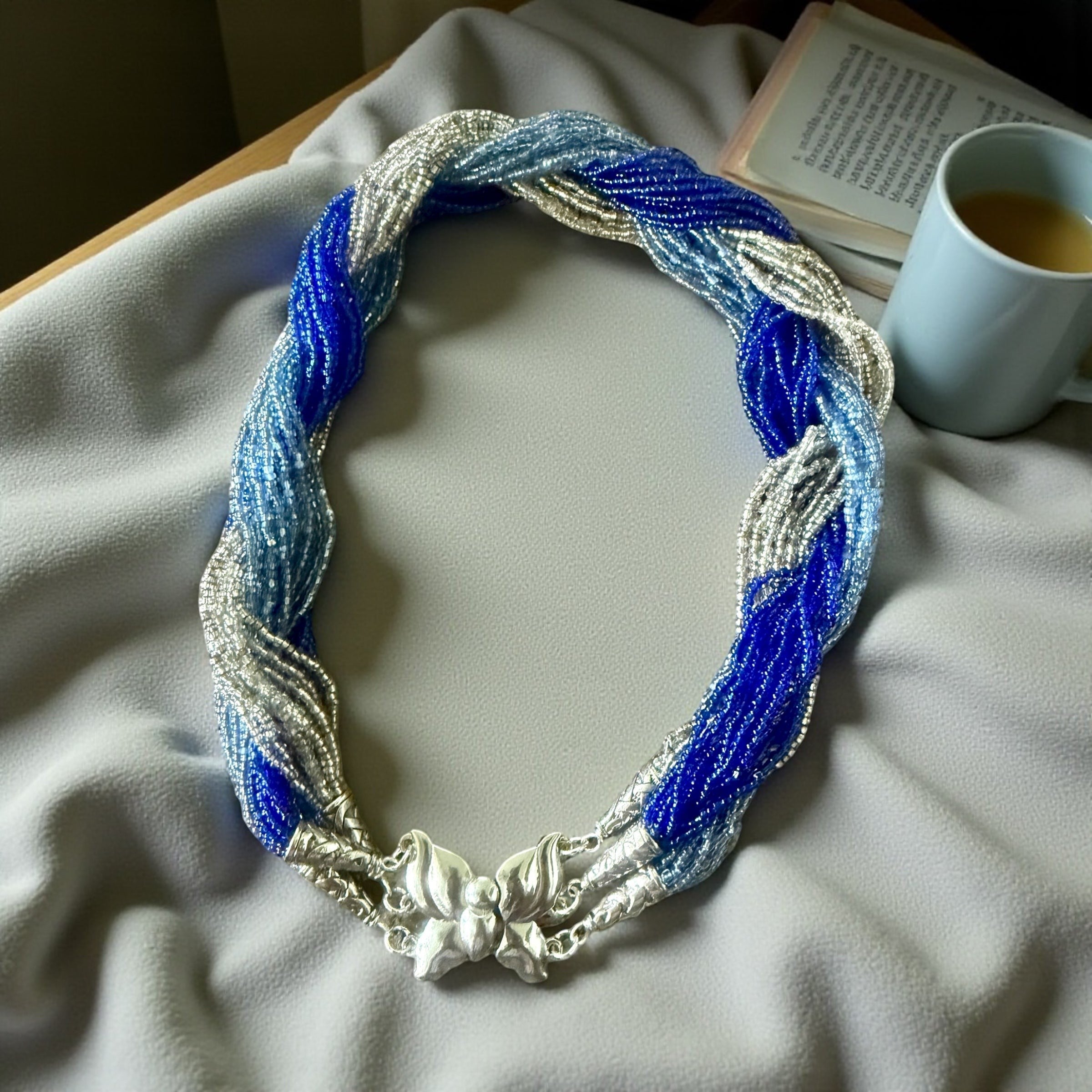 Jena Jewelry multi-strand braided necklace with blue and silver glass seed beads and a silver clasp.