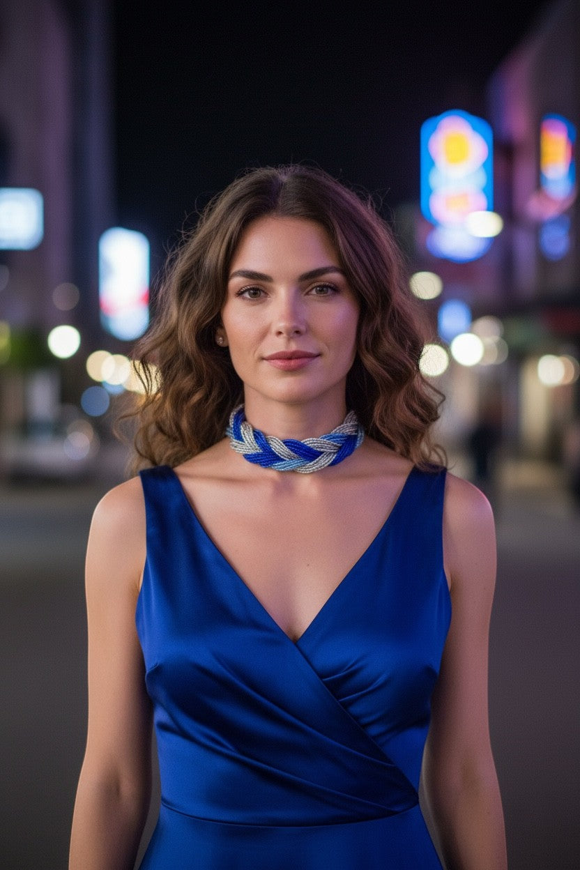 Jena Jewelry multi-strand braided glass seed bead necklace in blue and silver, worn by a model in a blue dress.