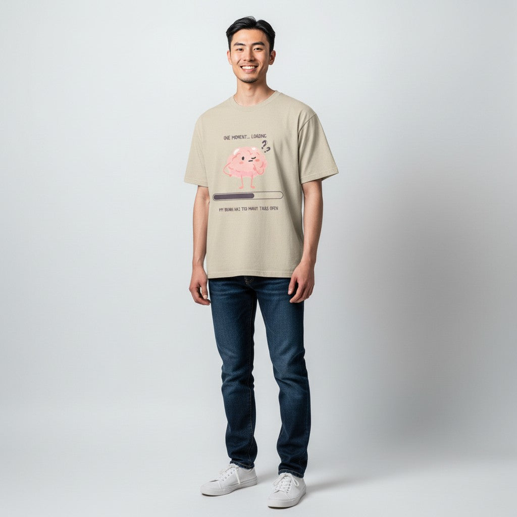 Jena Jewelry beige 100% cotton t-shirt with a graphic of a pink brain with question marks, a loading bar, and text "One Moment... Loading My Brain Has Too Many Tabs Open."