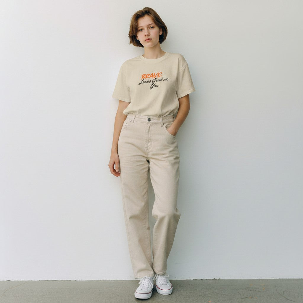 Jena Jewelry beige 100% cotton t-shirt with "BRAVE Looks Good on You" graphic print. Relaxed fit, crew neck.