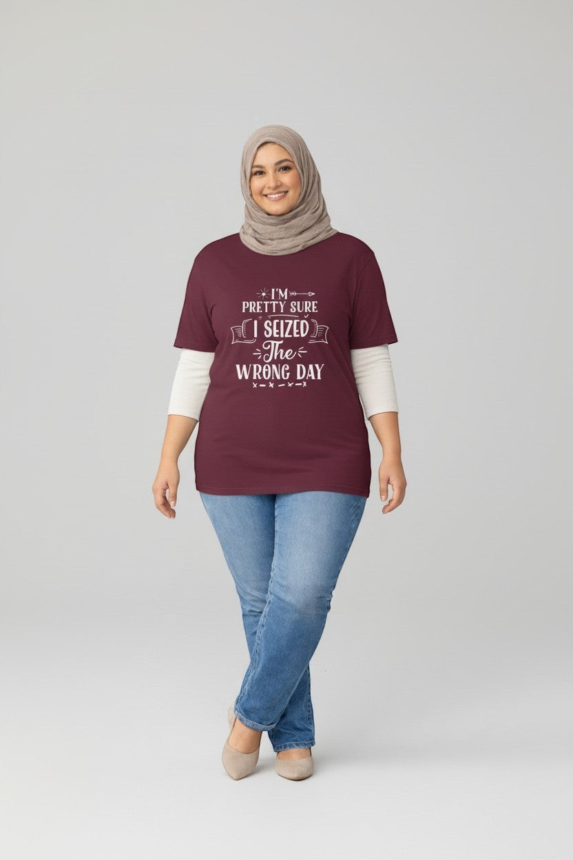 Jena Jewelry maroon 100% US cotton graphic tee with white text reading 'I'm pretty sure I seized the wrong day'. Model wears a hijab and jeans.