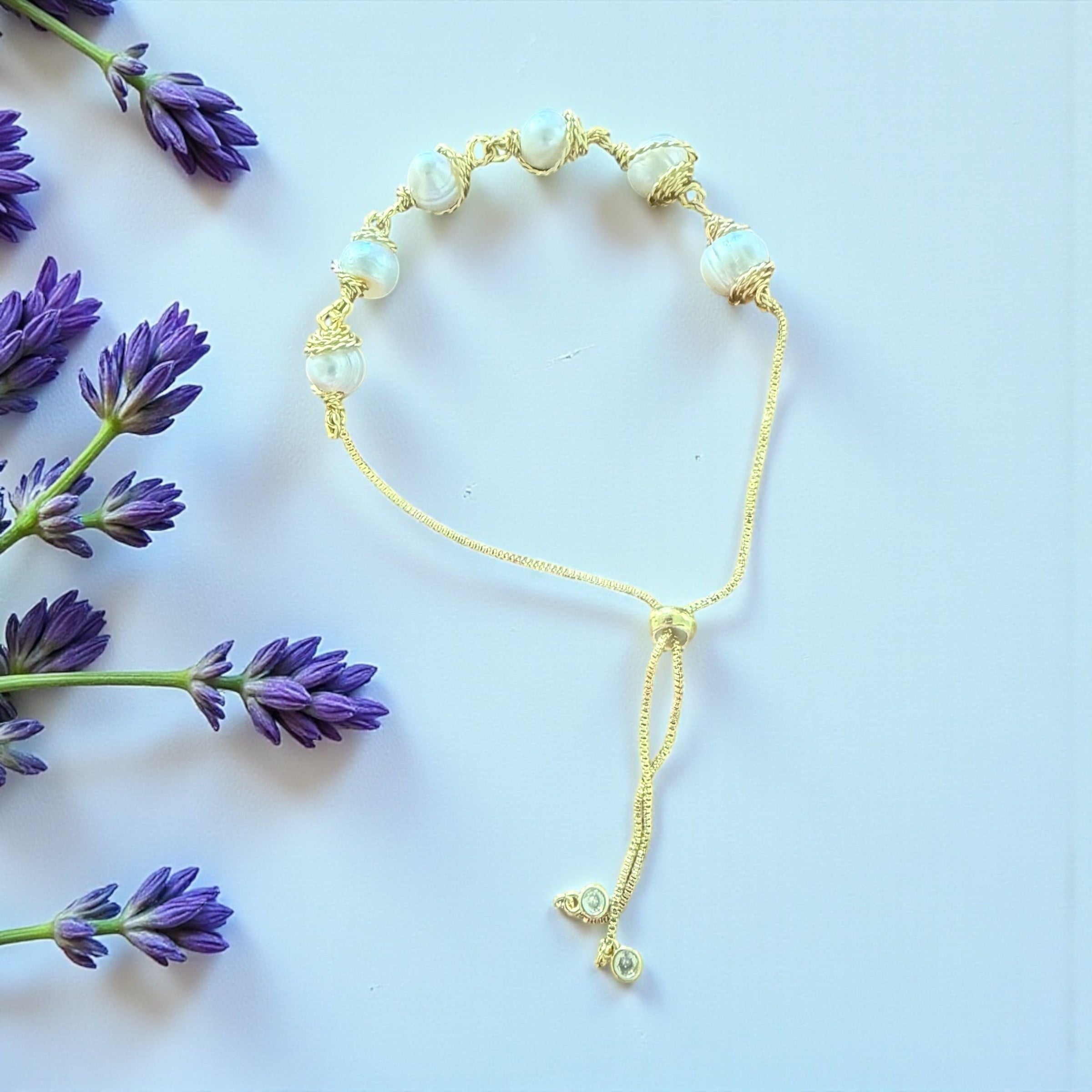 Jena Jewelry adjustable gold bracelet with six freshwater pearls and a sliding closure, accented by small clear crystals.