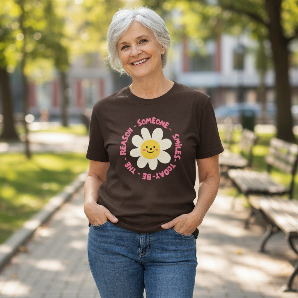 Jena Jewelry brown 100% cotton t-shirt with a smiling daisy graphic and "Be the Reason Someone Smiles Today" text.