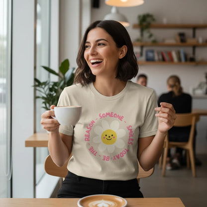 Jena Jewelry cream 100% cotton graphic tee with a smiling daisy and "Be the Reason Someone Smiles Today" text.