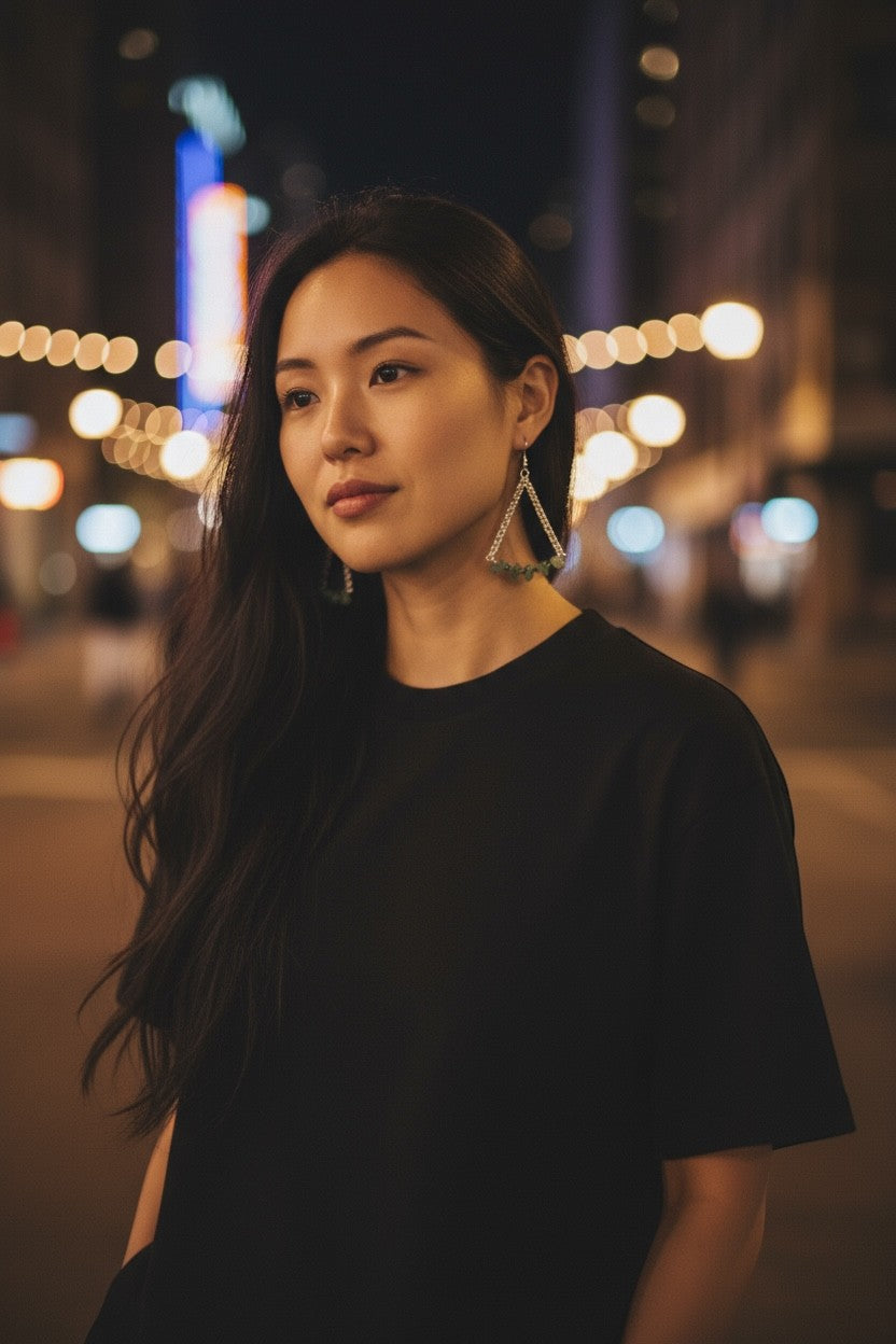 Jena Jewelry green aventurine and crystal quartz chainmaille triangle earrings worn by a woman at night.