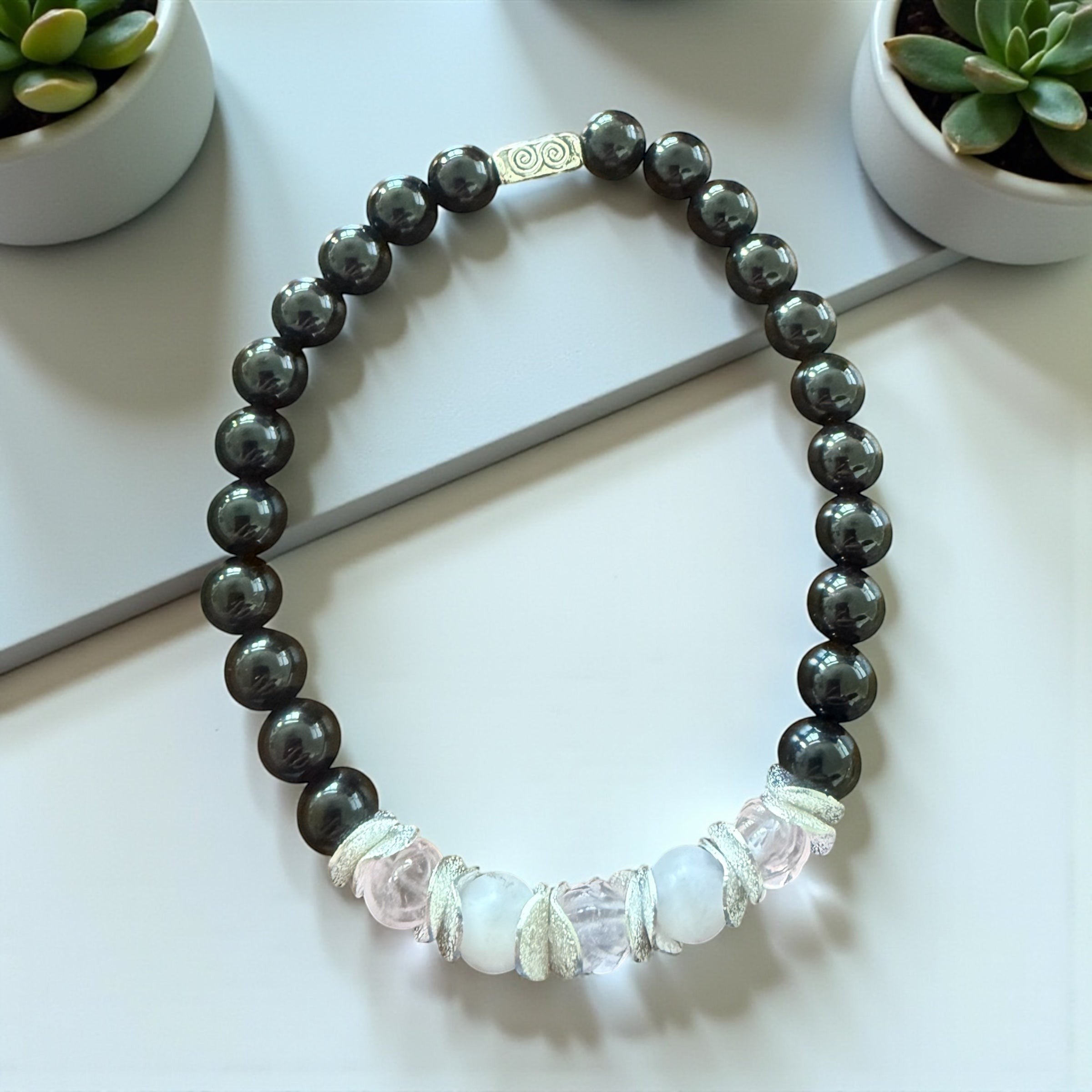 Jena Jewelry stretch bracelet with dark grey hematite beads and rose quartz accents, featuring a silver clasp.