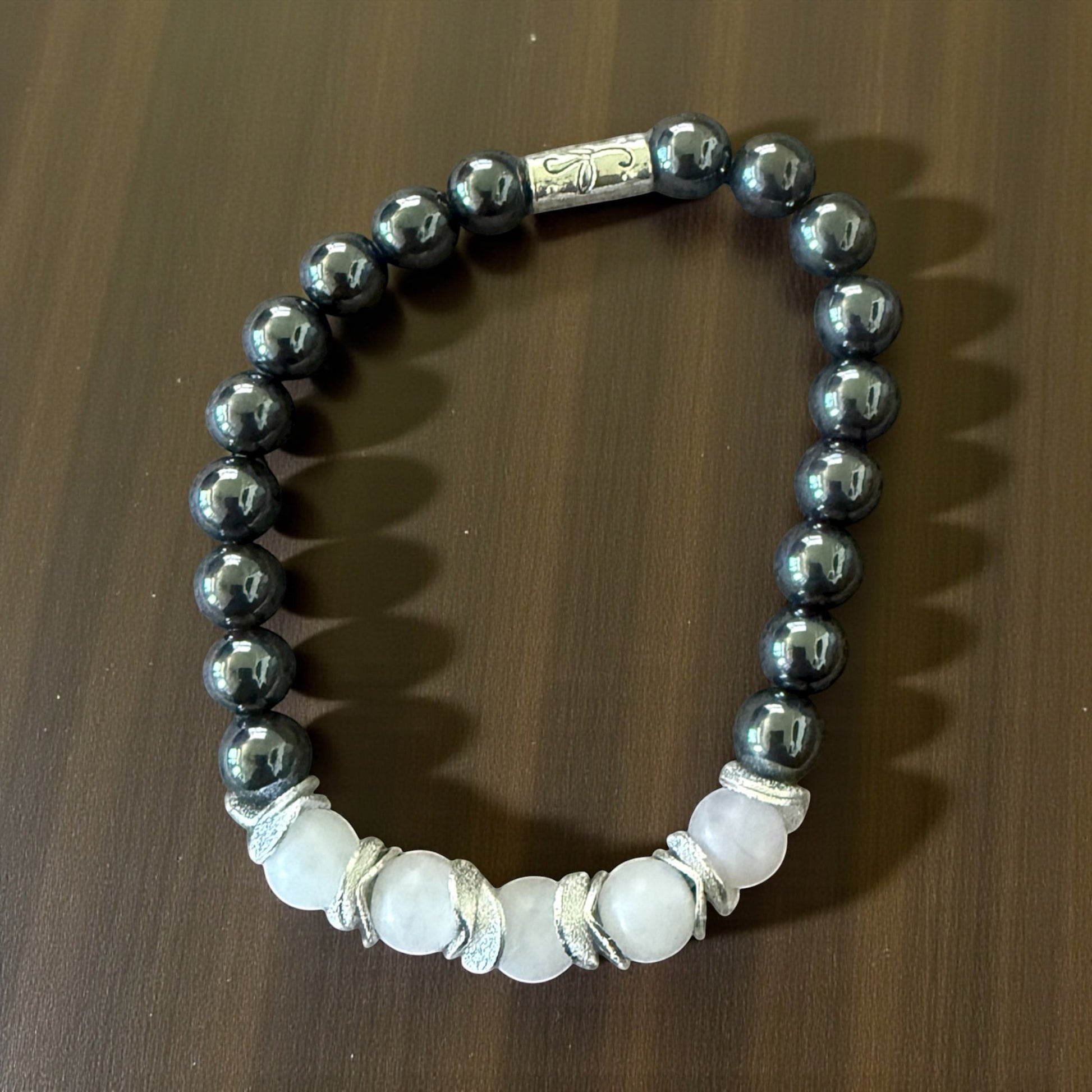Jena Jewelry hematite and white quartz stretch bracelet with silver accents. Features metallic grey hematite beads and pale pink quartz beads.