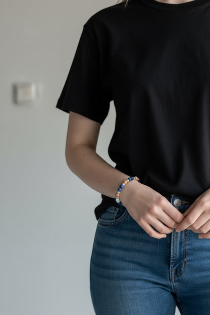 Jena Jewelry rosary bracelet with snow jade, lapis lazuli, sandalwood beads, and cross charm on a woman's wrist.
