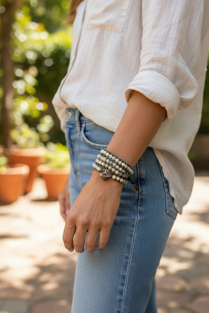 Jena Jewelry leather-wrapped bracelet with freshwater pearls, amethyst beads, and coconut button clasp on wrist.