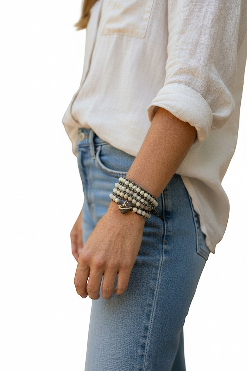 Jena Jewelry leather-wrapped bracelet with freshwater pearls, amethyst beads, and coconut button clasp on a woman's wrist.