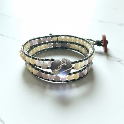 Jena Jewelry leather-wrapped bracelet with freshwater pearls, amethyst beads, and coconut button clasp, featuring a heart-shaped amethyst pendant.
