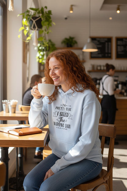 Light blue cotton-poly blend hoodie with a funny quote "I'm Pretty Sure I Seized the Wrong Day" printed on the chest. Model is wearing jeans and holding a mug.