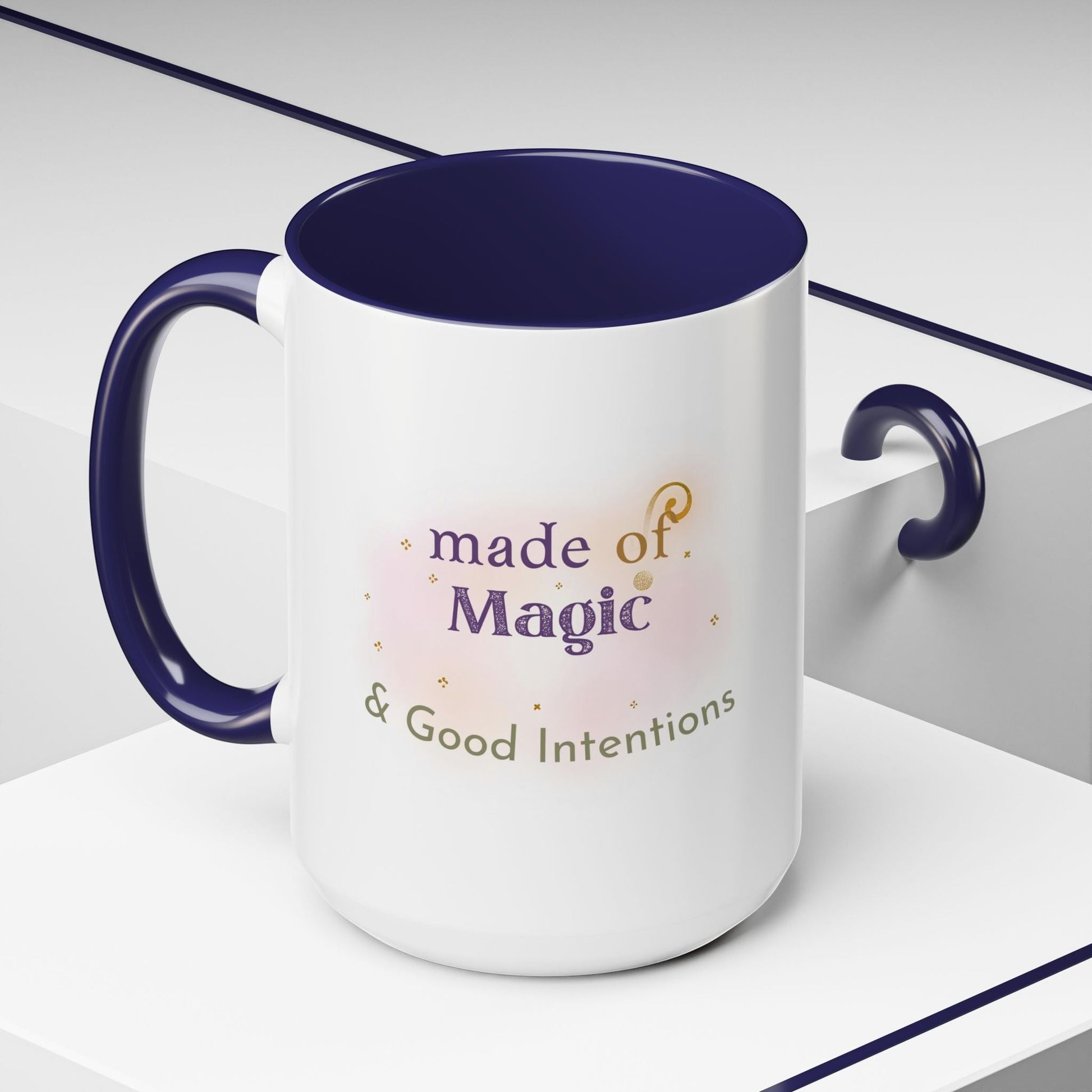 Jena Jewelry white ceramic mug with navy blue interior and handle, featuring "Made of Magic & Good Intentions" text and watercolor accents.