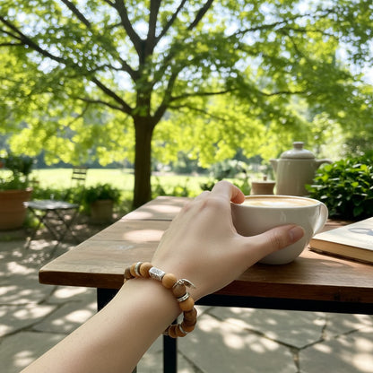 Jena Jewelry Tiger Ebony & Thuja Sutchuenensis wood mala bracelet on wrist, with silver accents, outdoors setting.