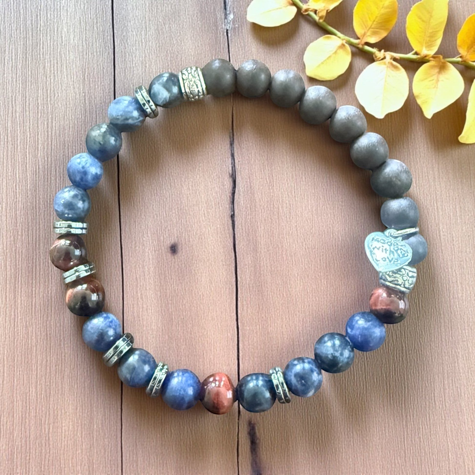 Jena Jewelry bracelet with lapis lazuli, hematite, ebony wood, and red tiger eye beads spelling 'Breathe' in Morse code. Features a 'Made With Love' heart charm.