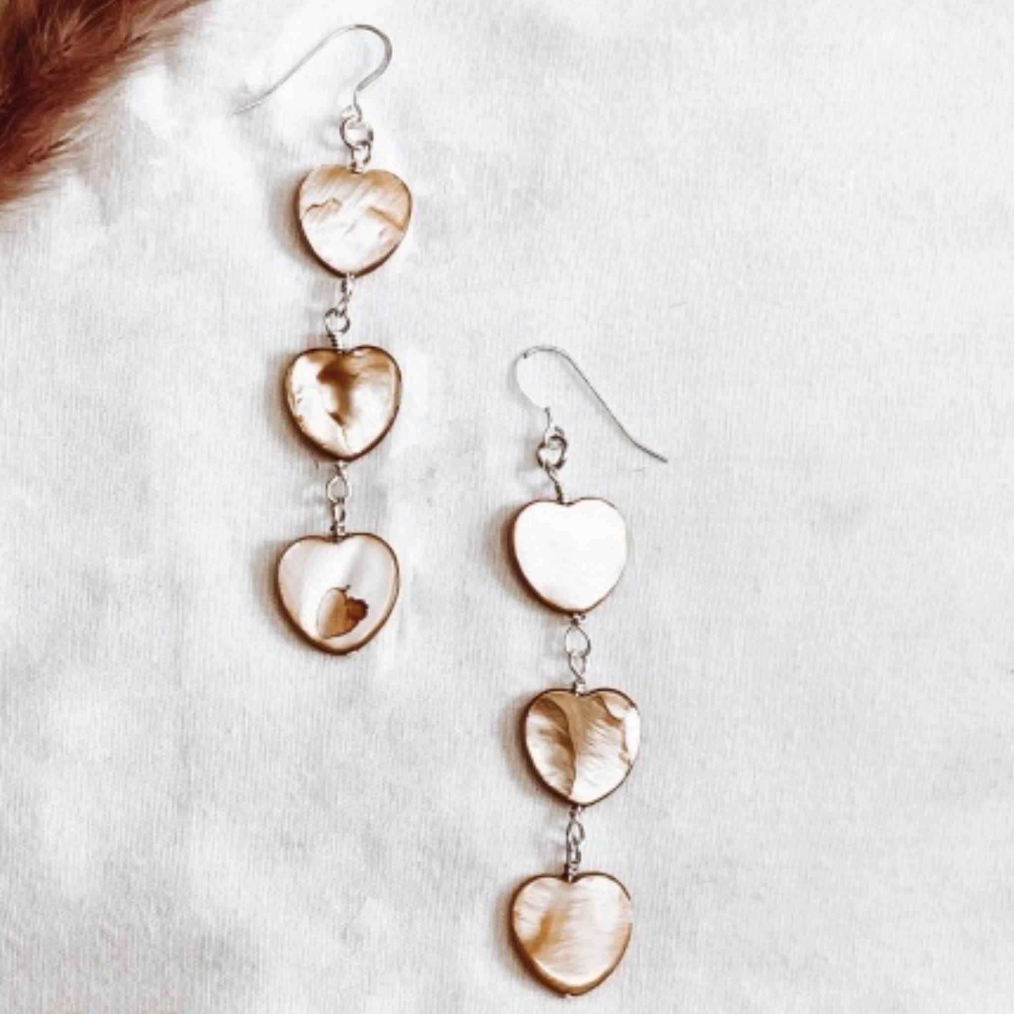 Jena Jewelry tea-dyed mother of pearl heart dangle earrings with iridescent glow and vintage warmth.