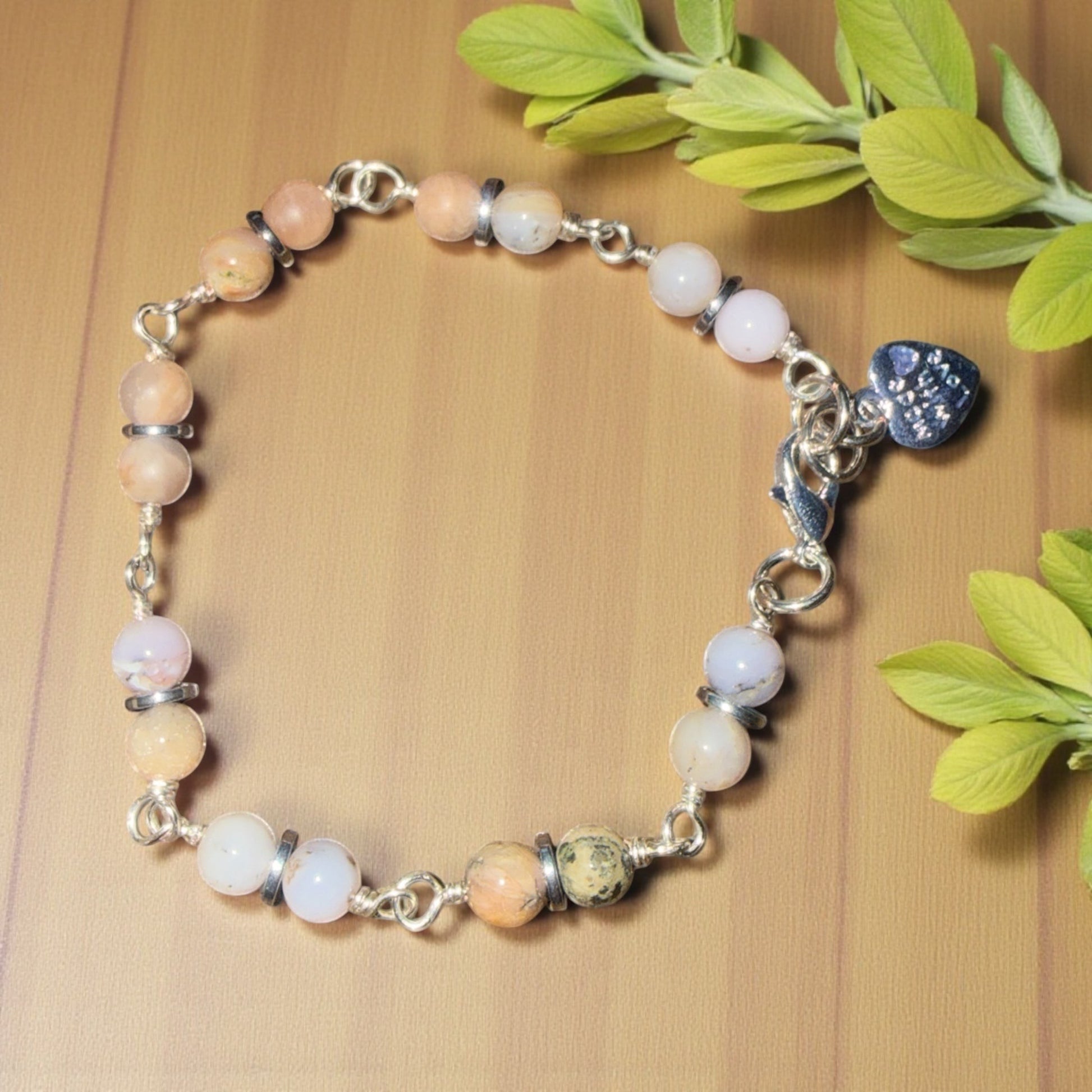Jena Jewelry multi-stone bracelet with pink, white, and blue beads, silver wire wrapping, and a blue heart charm.