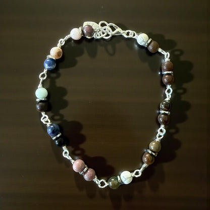 Jena Jewelry multi-stone bracelet with silver wire wrapping and clasp. Features stones in pink, blue, white, and brown.