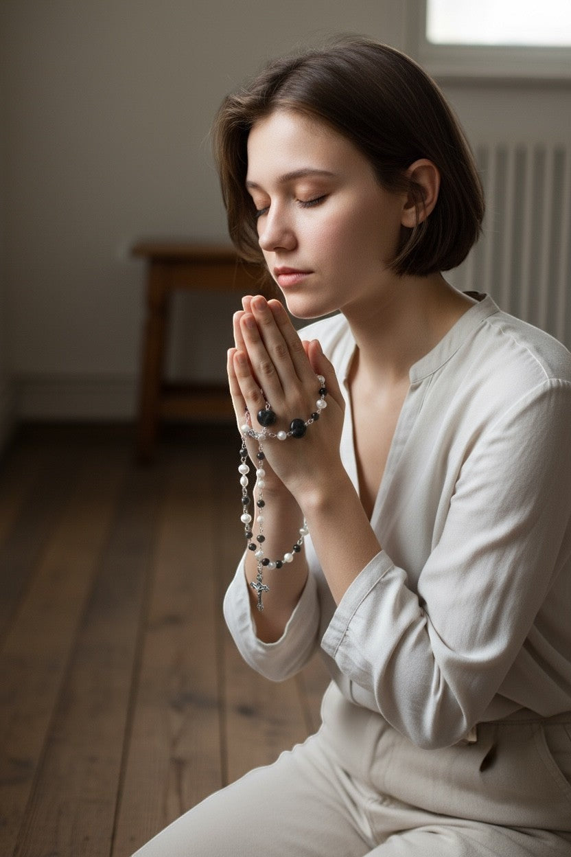 Jena Jewelry rosary with freshwater pearls, black onyx, and porcelain heart beads, held by a woman praying.