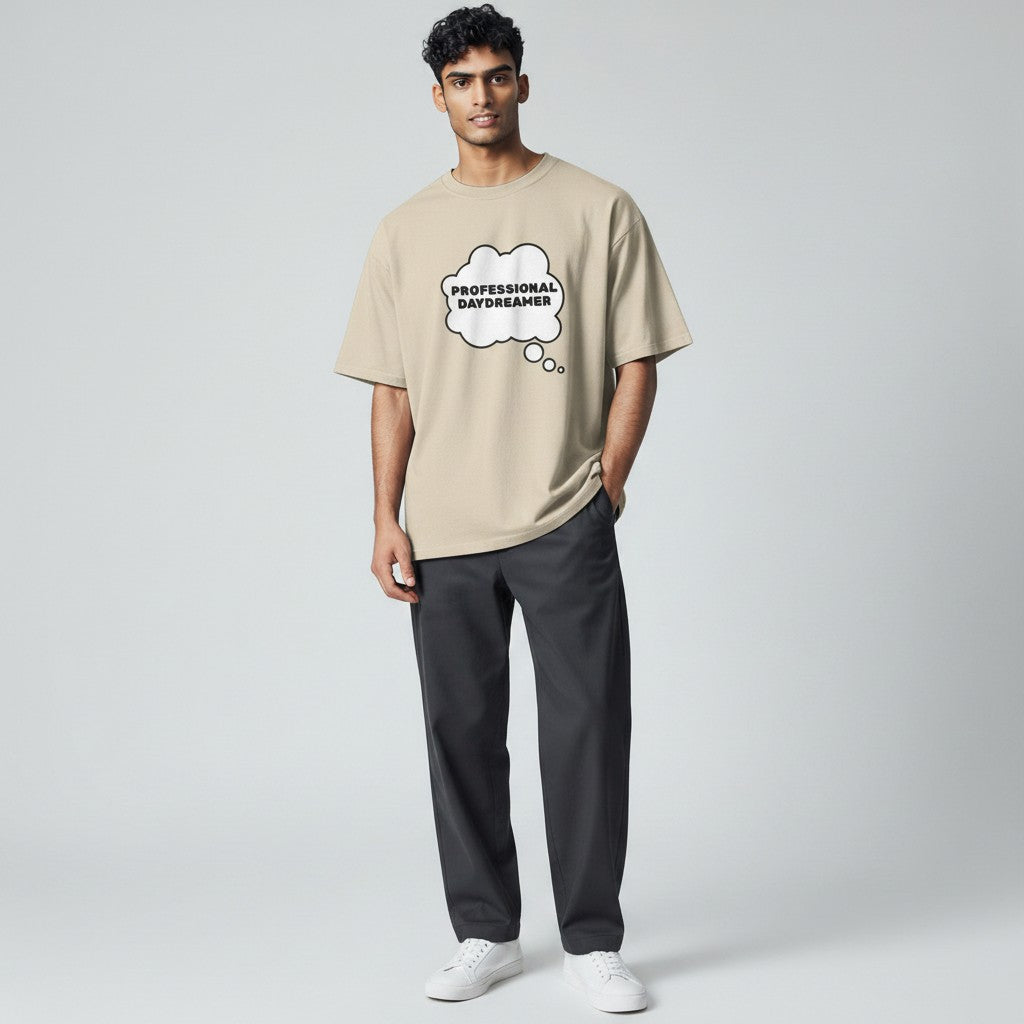 Jena Jewelry beige 100% cotton t-shirt with "PROFESSIONAL DAYDREAMER" graphic in a thought bubble.