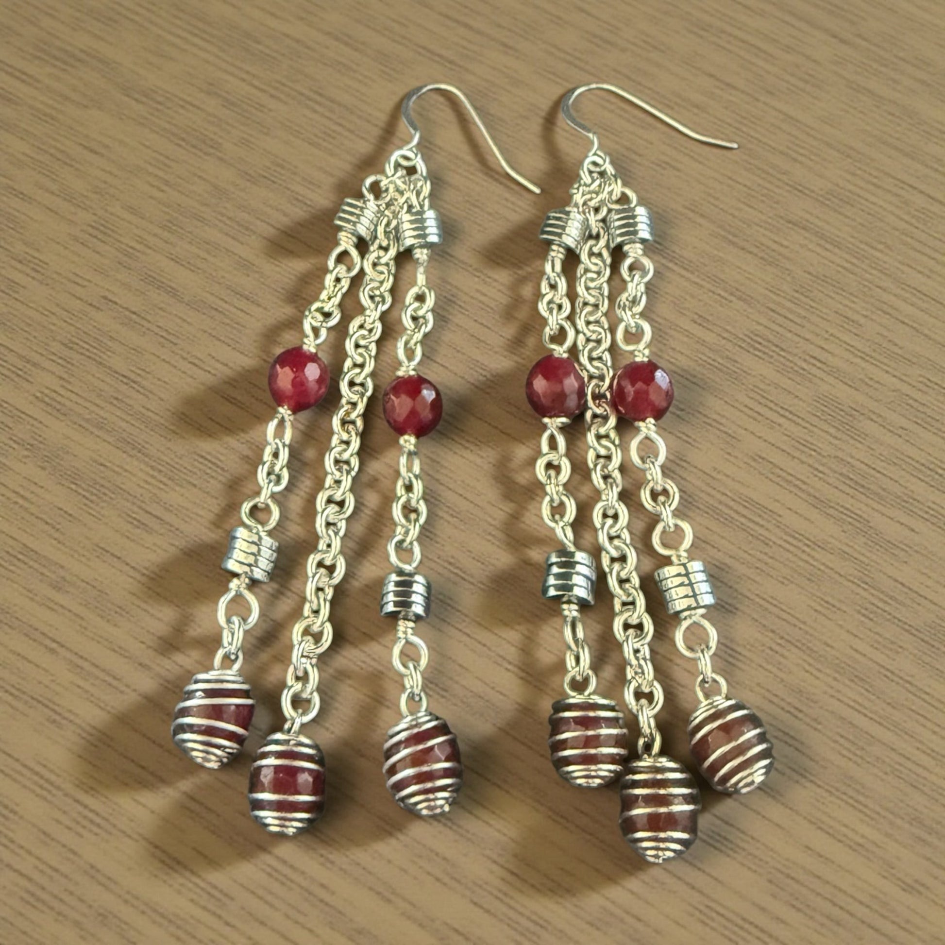 Jena Jewelry cascading red gemstone and silver strand earrings, 4 inches long, with faceted beads and striped barrel charms.