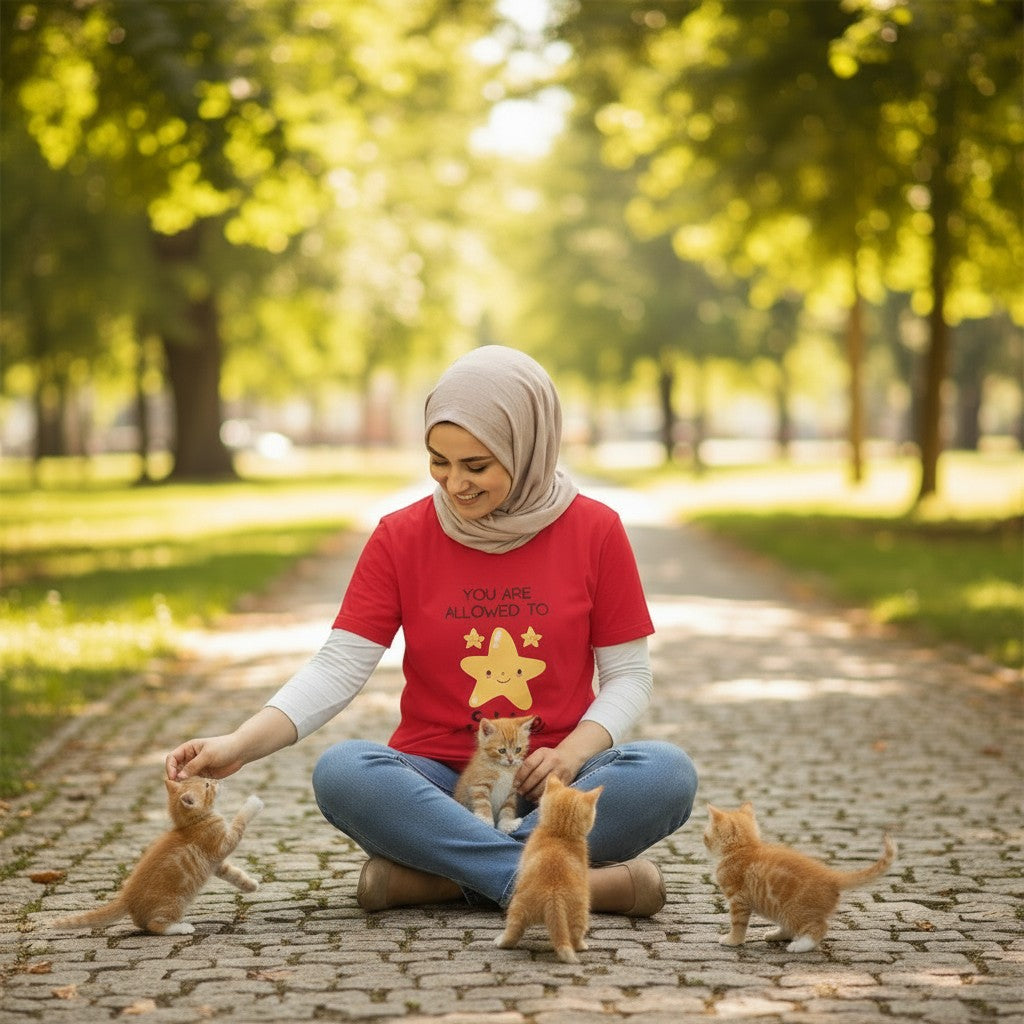Jena Jewelry red 100% cotton t-shirt with "You Are Allowed to Shine" graphic and smiling star. Model wears it with jeans and a hijab.