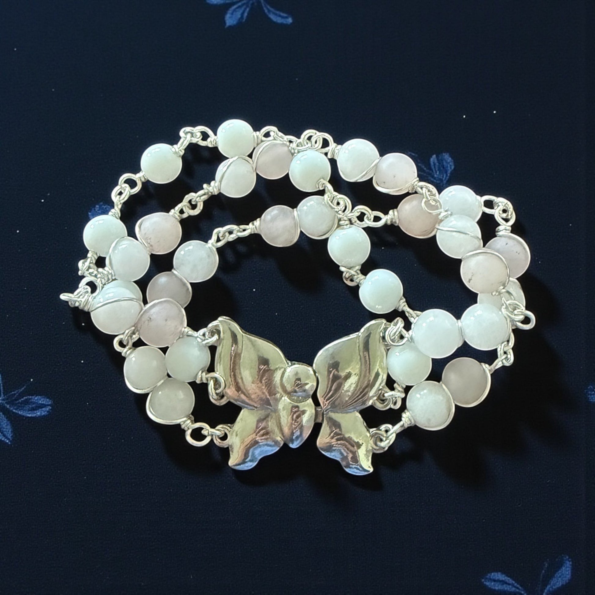 Jena Jewelry Rose Quartz and Snow Jade bracelet with silver butterfly clasp. Delicate beads symbolize love and transformation.
