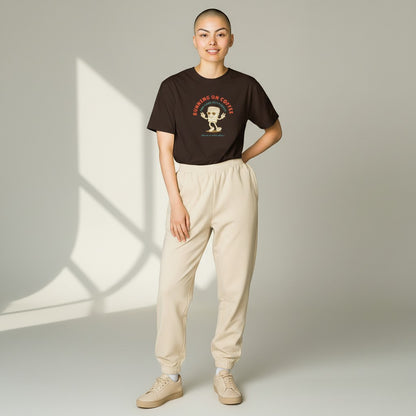 Jena Jewelry brown 100% cotton t-shirt with a retro graphic of a smiling coffee cup wearing sunglasses and giving peace signs. Text reads "RUNNING ON COFFEE AND GOOD INTENTIONS".