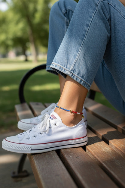 Jena Jewelry handmade seed bead anklet with blue, red, white beads and gold stars, worn with jeans and white sneakers.