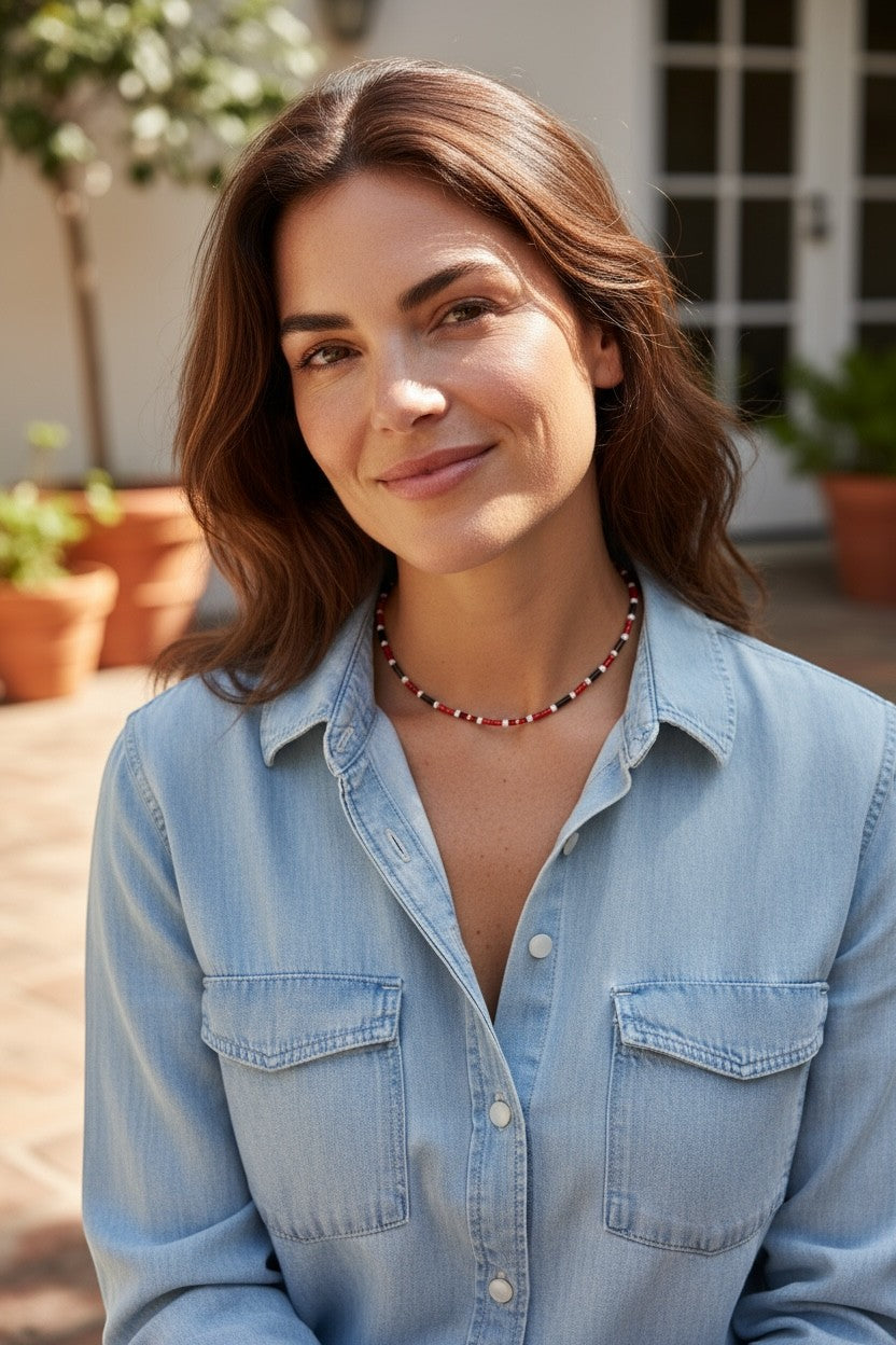 Jena Jewelry red, white, and black seed bead choker necklace on a woman wearing a denim shirt.