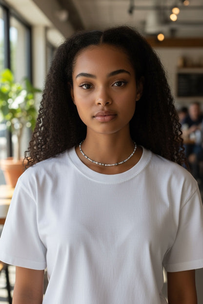 Jena Jewelry delicate seed bead necklace with pearl and grey beads on a woman wearing a white t-shirt.