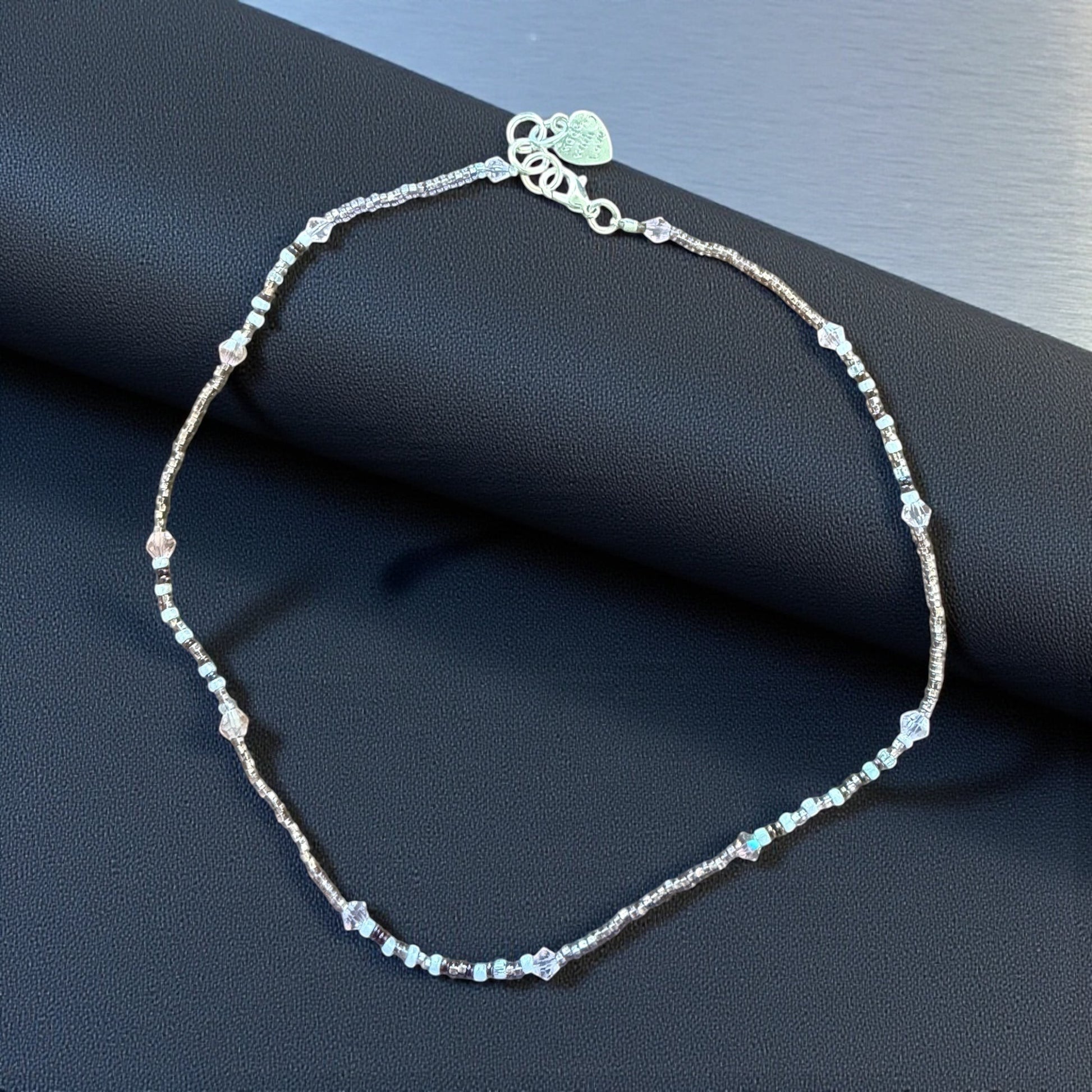 Jena Jewelry delicate seed bead necklace with white, pink, and clear crystal beads. Features a silver clasp and heart charm.