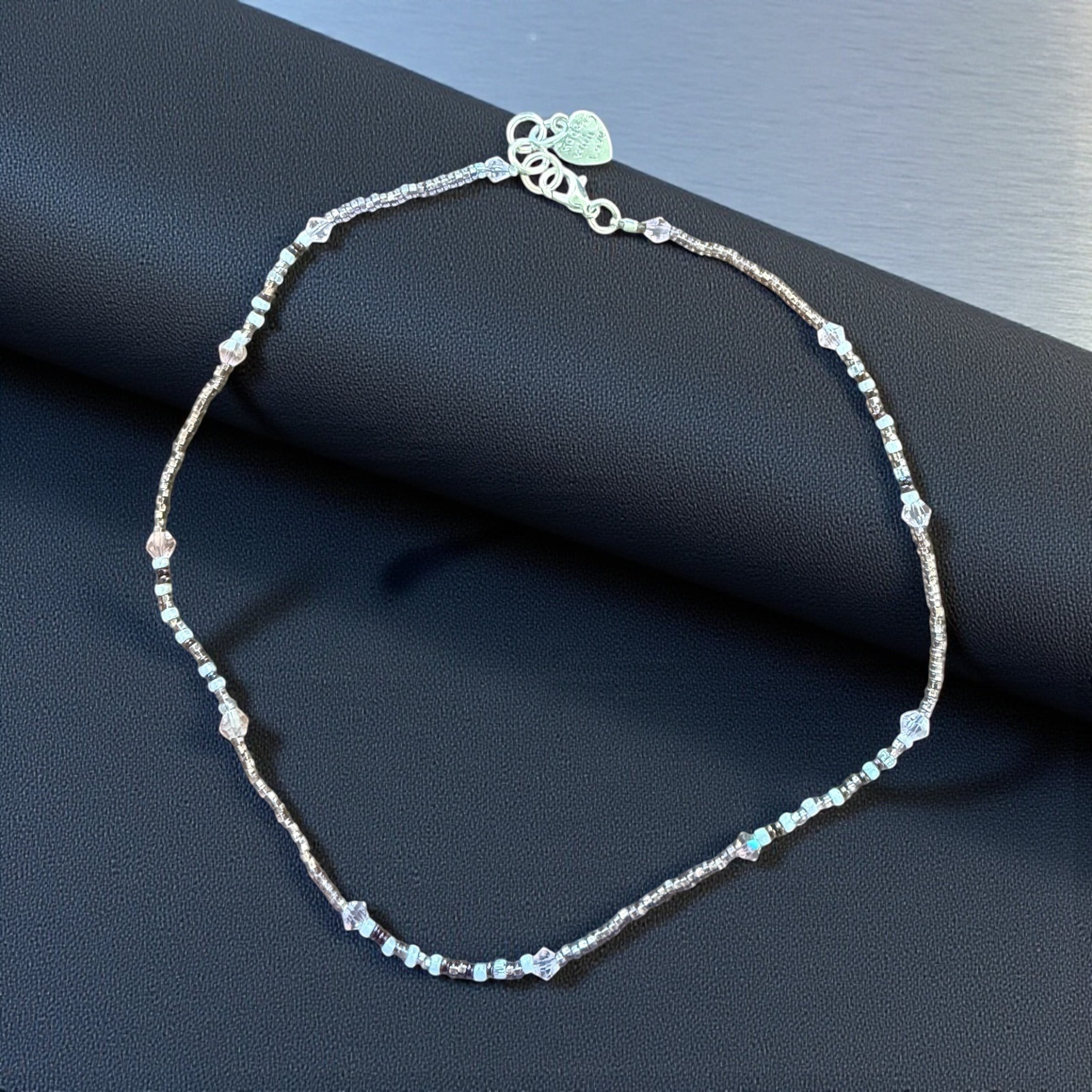 Jena Jewelry delicate seed bead necklace with white, pink, and clear crystal beads. Features a silver clasp and heart charm.
