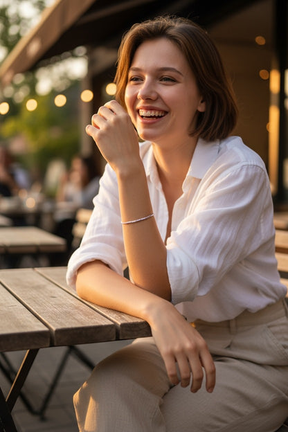 Jena Jewelry small seed bead bracelet in light purple, worn by a smiling woman sitting at an outdoor cafe.