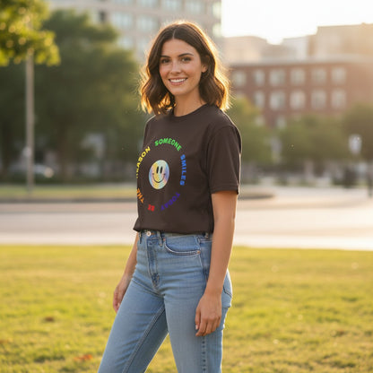 Jena Jewelry brown 100% cotton t-shirt with a rainbow smiley face graphic and "Be The Reason Someone Smiles Today" text.
