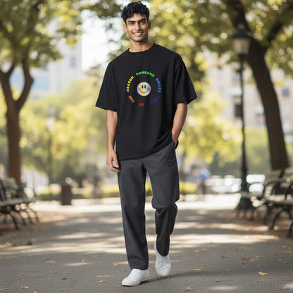 Jena Jewelry black 100% cotton t-shirt with a rainbow smiley face graphic and text that reads "Be The Reason Someone Smiles Today".